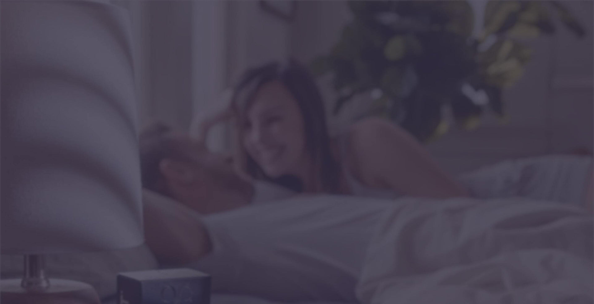 Happy couple in bed and enjoying longer lasting intimacy with Promescent premium products